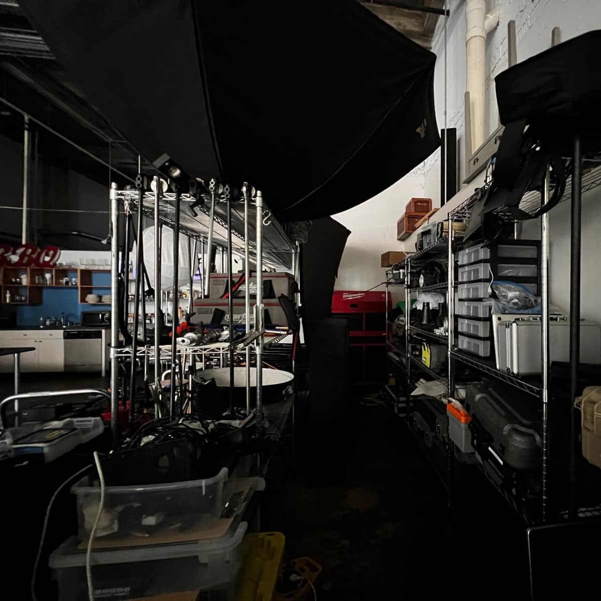 A dimly lit storage area with metal shelves lined with various equipment cases and tools.