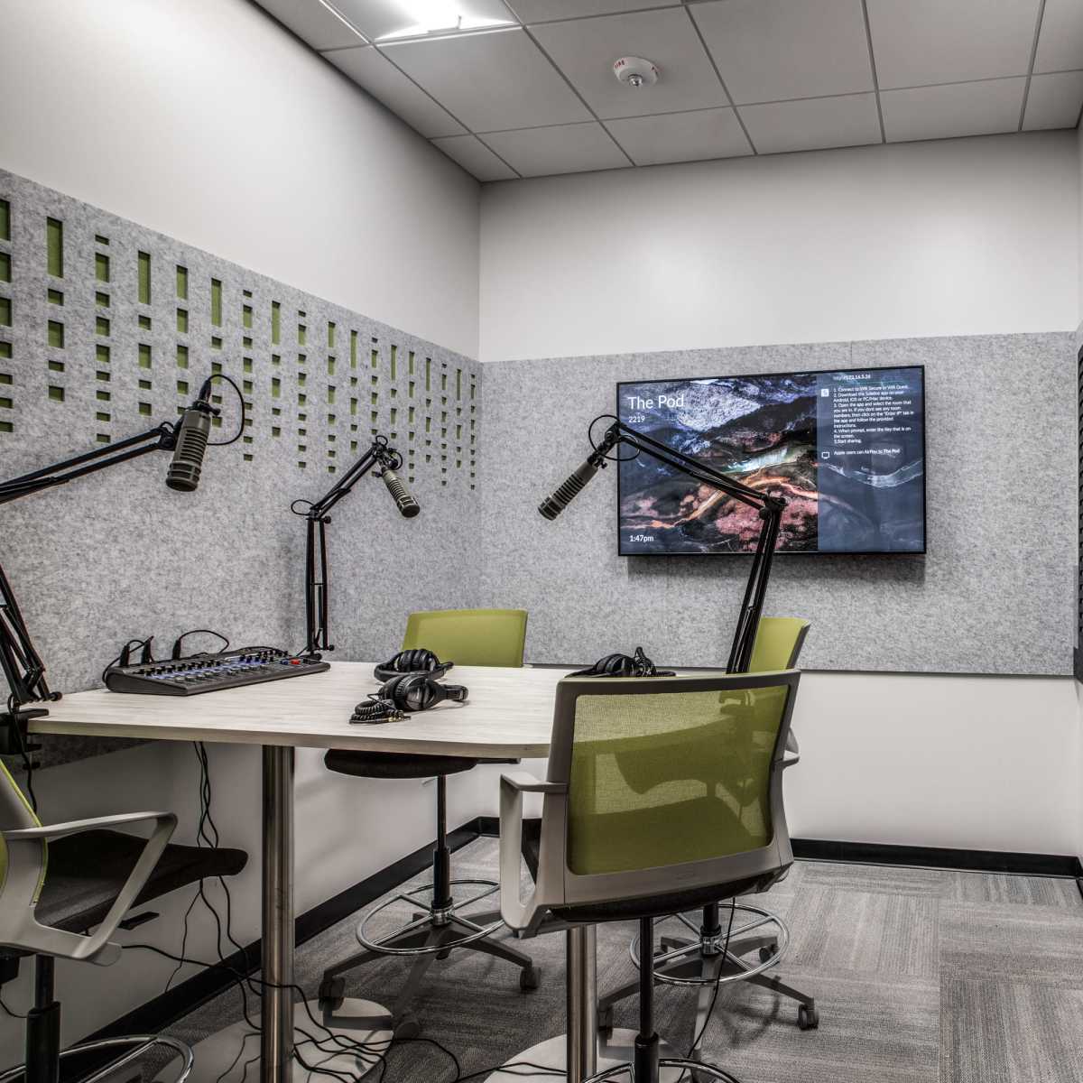 A small meeting room equipped with a large screen, microphones, and seating for discussions.