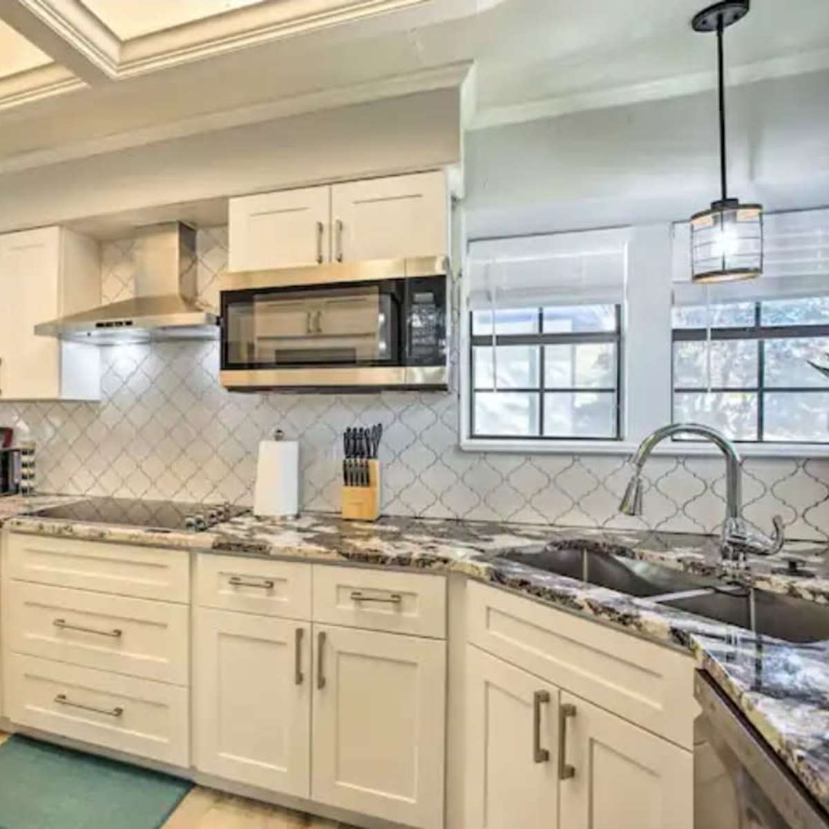A modern kitchen featuring white cabinetry, stainless steel appliances, and a marble countertop.