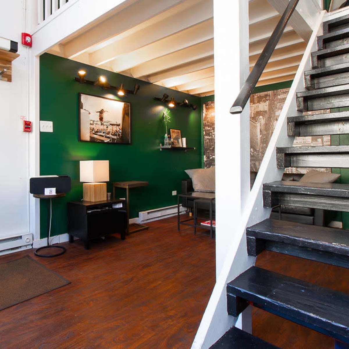 A small entryway with a coat rack on the left, a green accent wall, and a staircase on the right leading to an upper level.