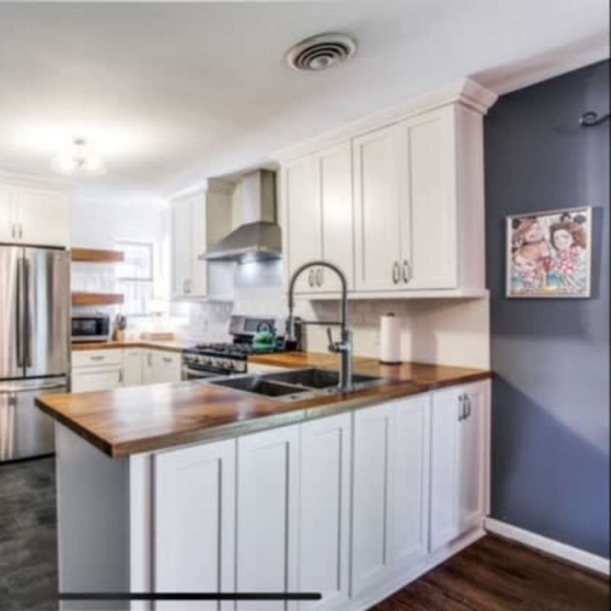 The kitchen features white cabinetry, stainless steel appliances, and a wooden countertop with an island.