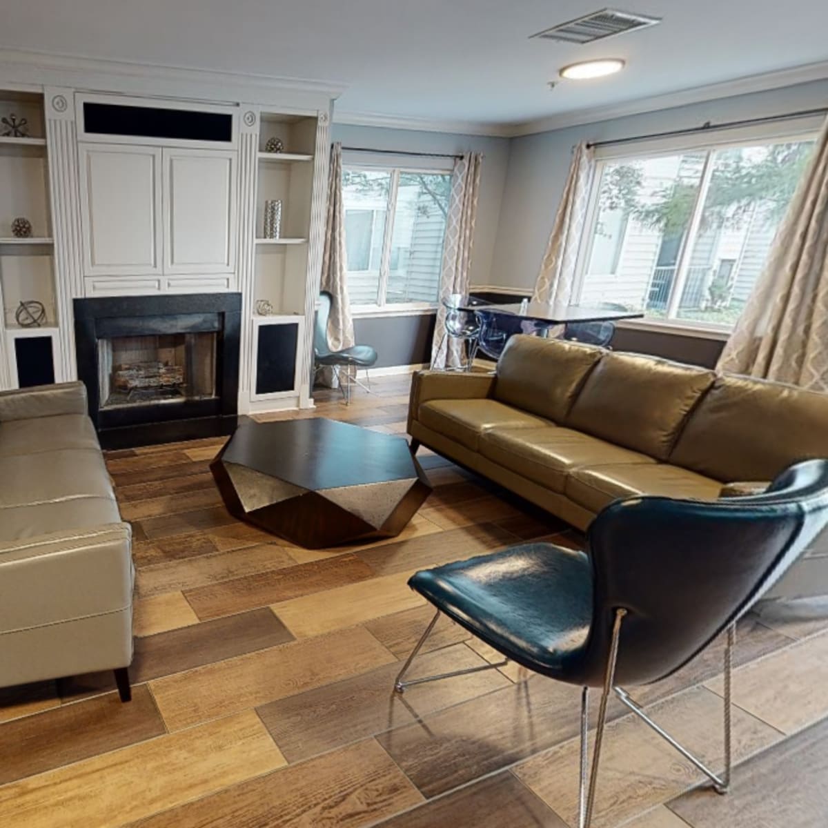 A modern living room with two light-gray sofas, a dark wooden coffee table, and a fireplace, all arranged around a window.