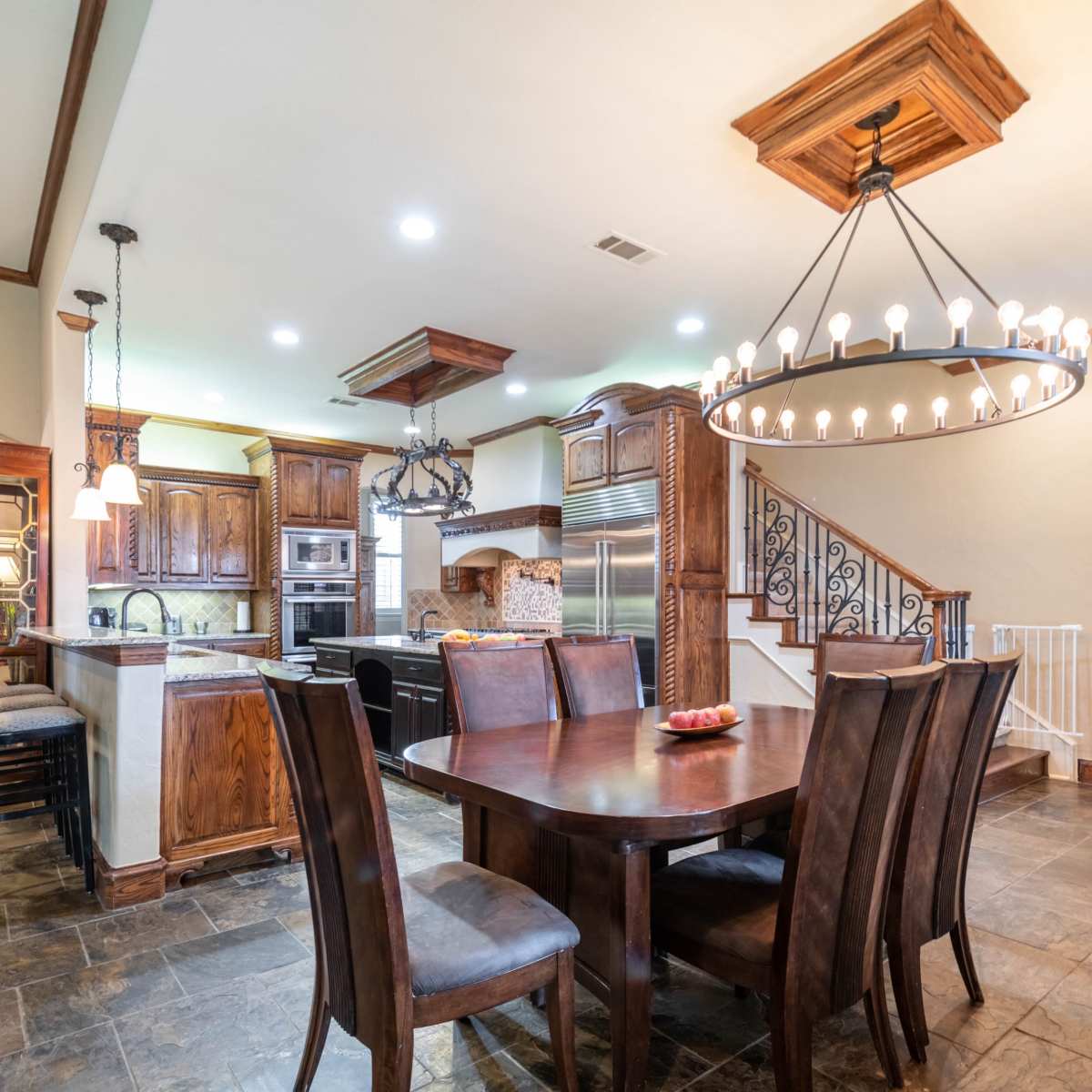 A spacious kitchen and dining area features dark wooden cabinetry, a large table, and a decorative chandelier.