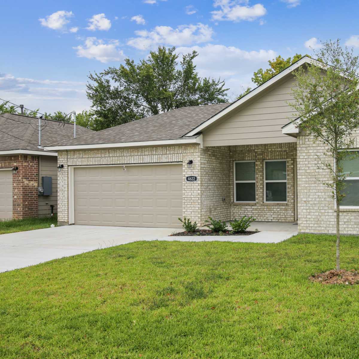 A single-story brick house with a two-car garage and a well-manicured lawn.