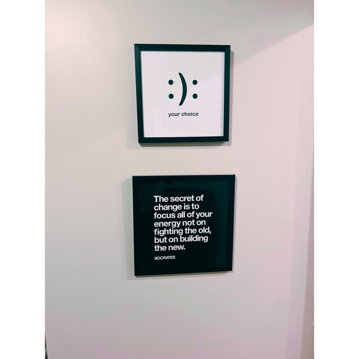 Two framed quotes on a wall; the top frame features a smiley face and the words "your choice," while the bottom frame contains a quote attributed to Socrates about change.