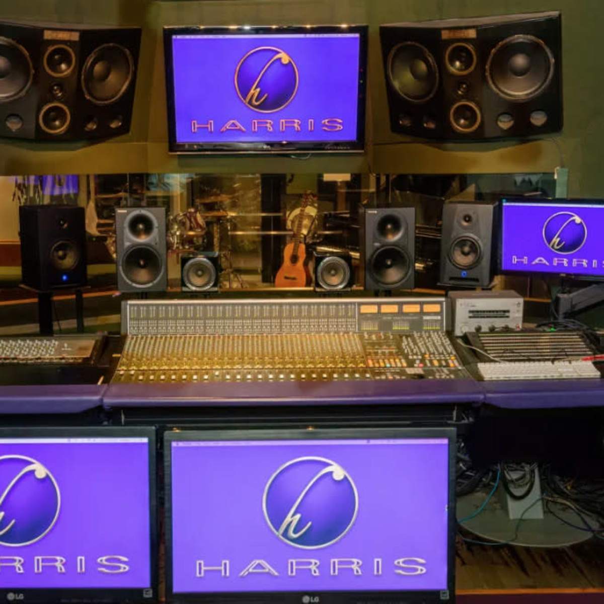 A sound studio setup featuring a mixing console, multiple monitors, and high-quality speakers arranged around a central workspace.