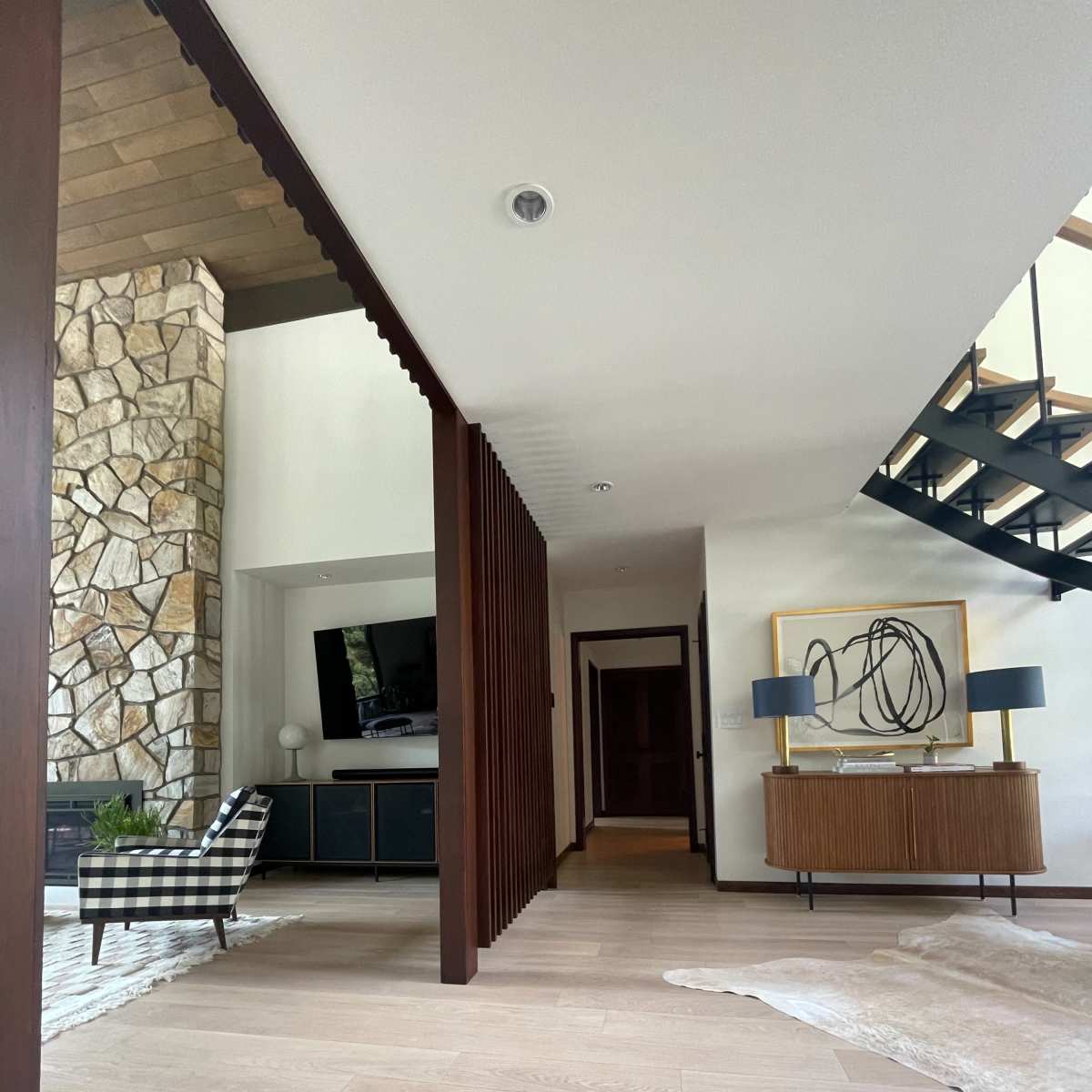 A modern living space featuring a stone wall, a staircase, and a combination of wooden furniture and decor.