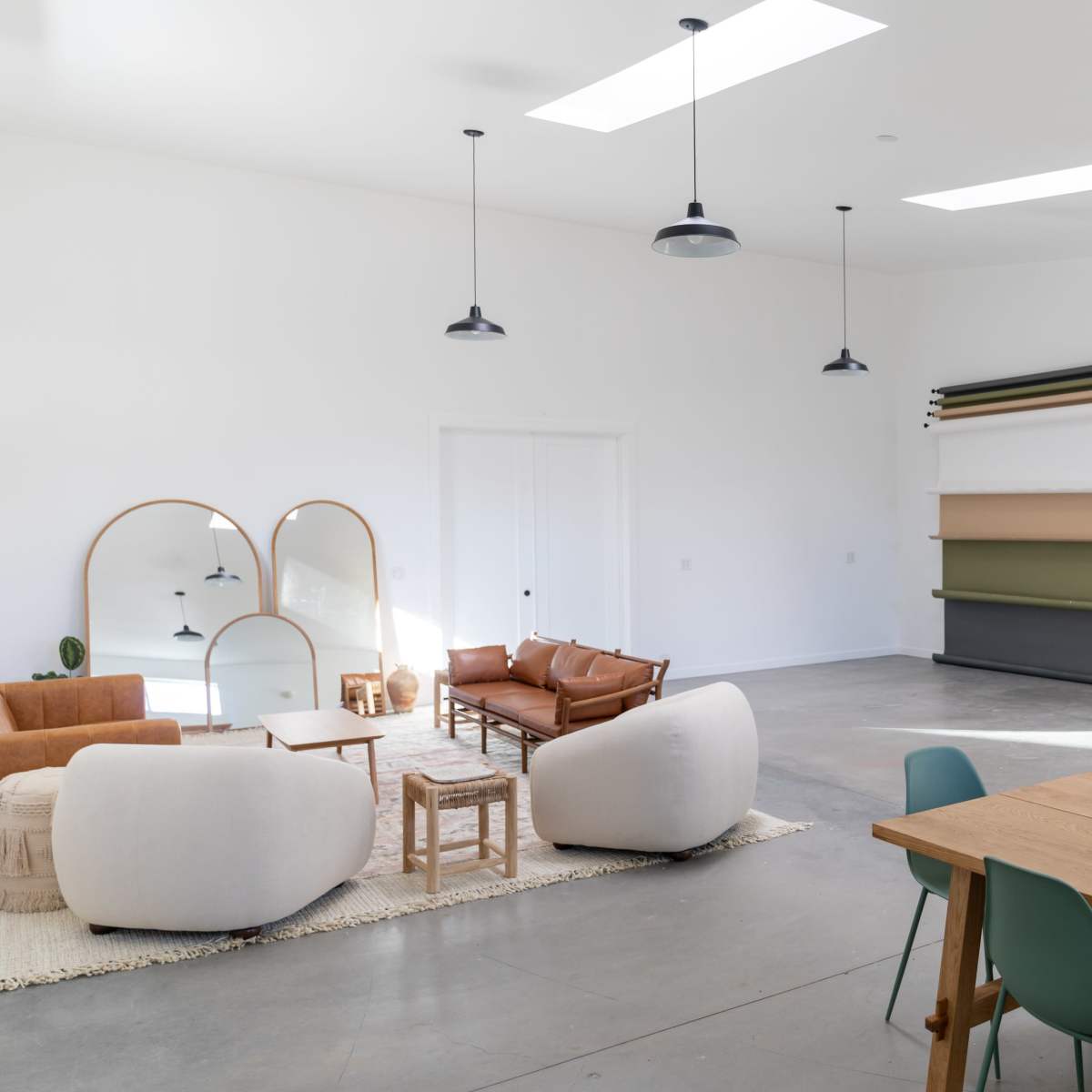 A modern, bright interior space featuring a seating area with sofas, a dining table, and a variety of decorative elements.