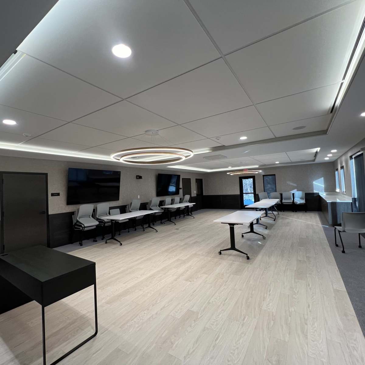 A modern conference room featuring a large oval light fixture, multiple tables, and chairs arranged for meetings.