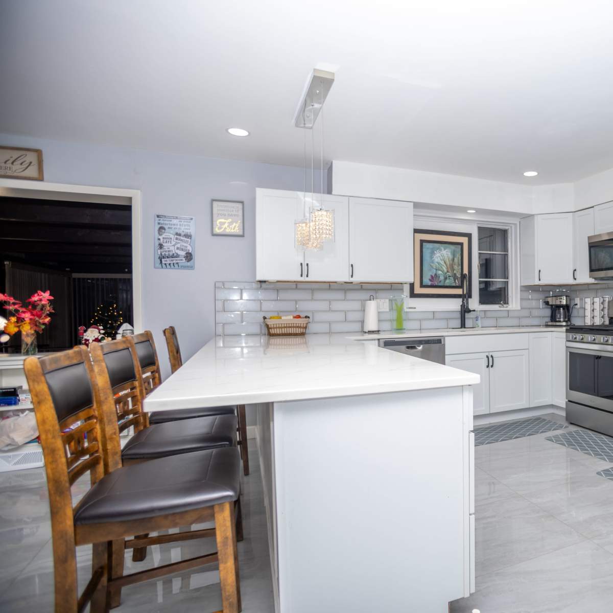 The kitchen features modern appliances, a long island with bar seating, and white cabinetry with gray countertops.