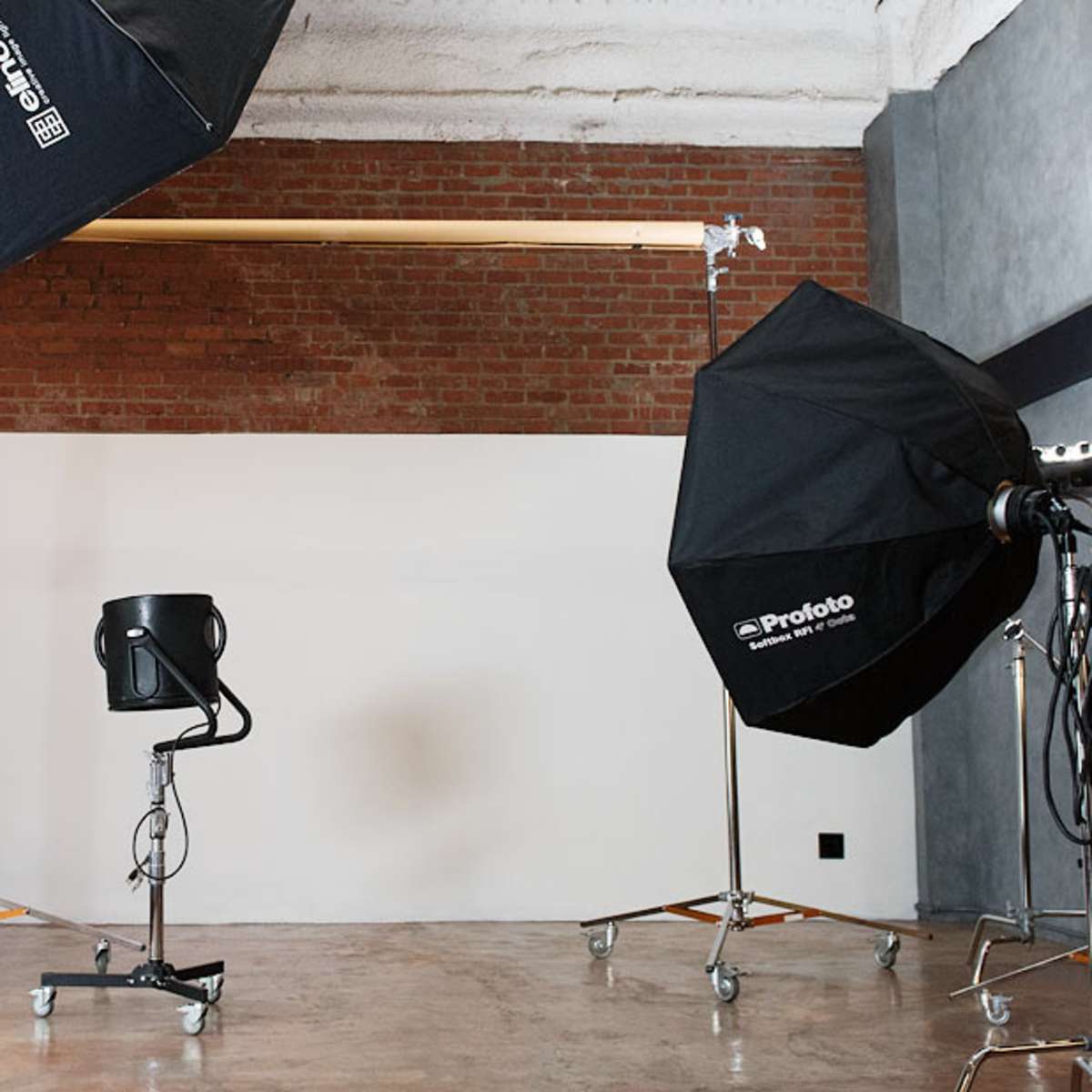 A photography studio setup with two large light softboxes, a black chair, and a plain white backdrop.