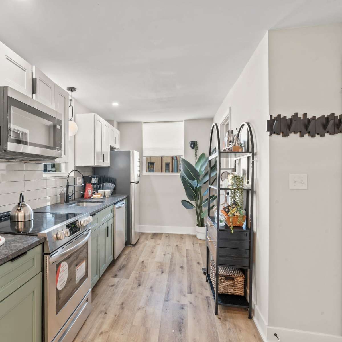 The kitchen features light-colored cabinetry, stainless steel appliances, a stone countertop, and a small dining area with a platter of snacks.