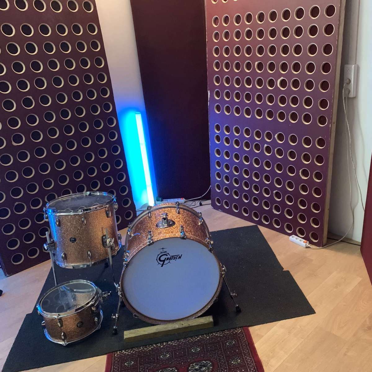 A music recording studio setup featuring a drum kit and soundproofing panels.