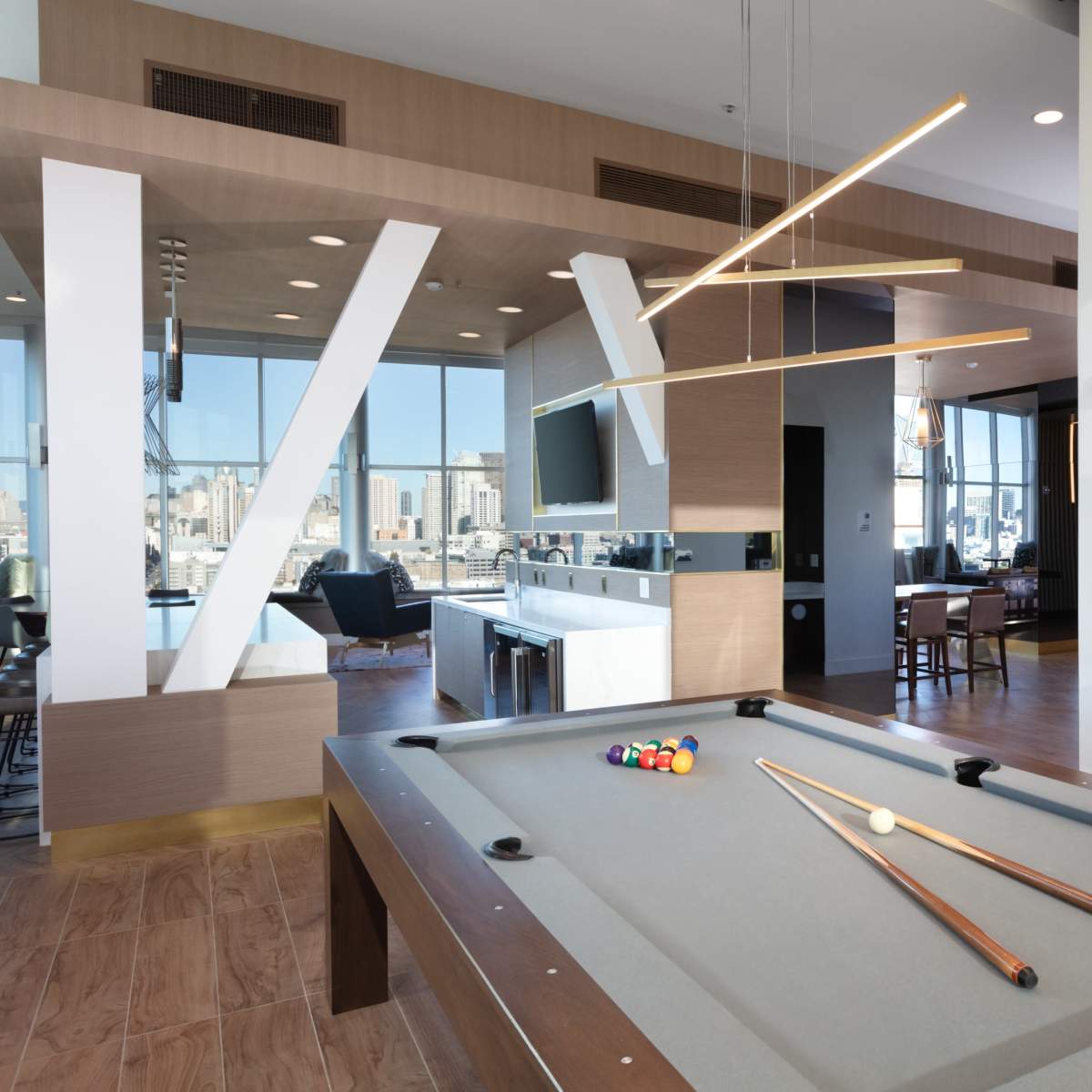 A modern game room featuring a pool table, sleek furniture, and large windows with a city view.