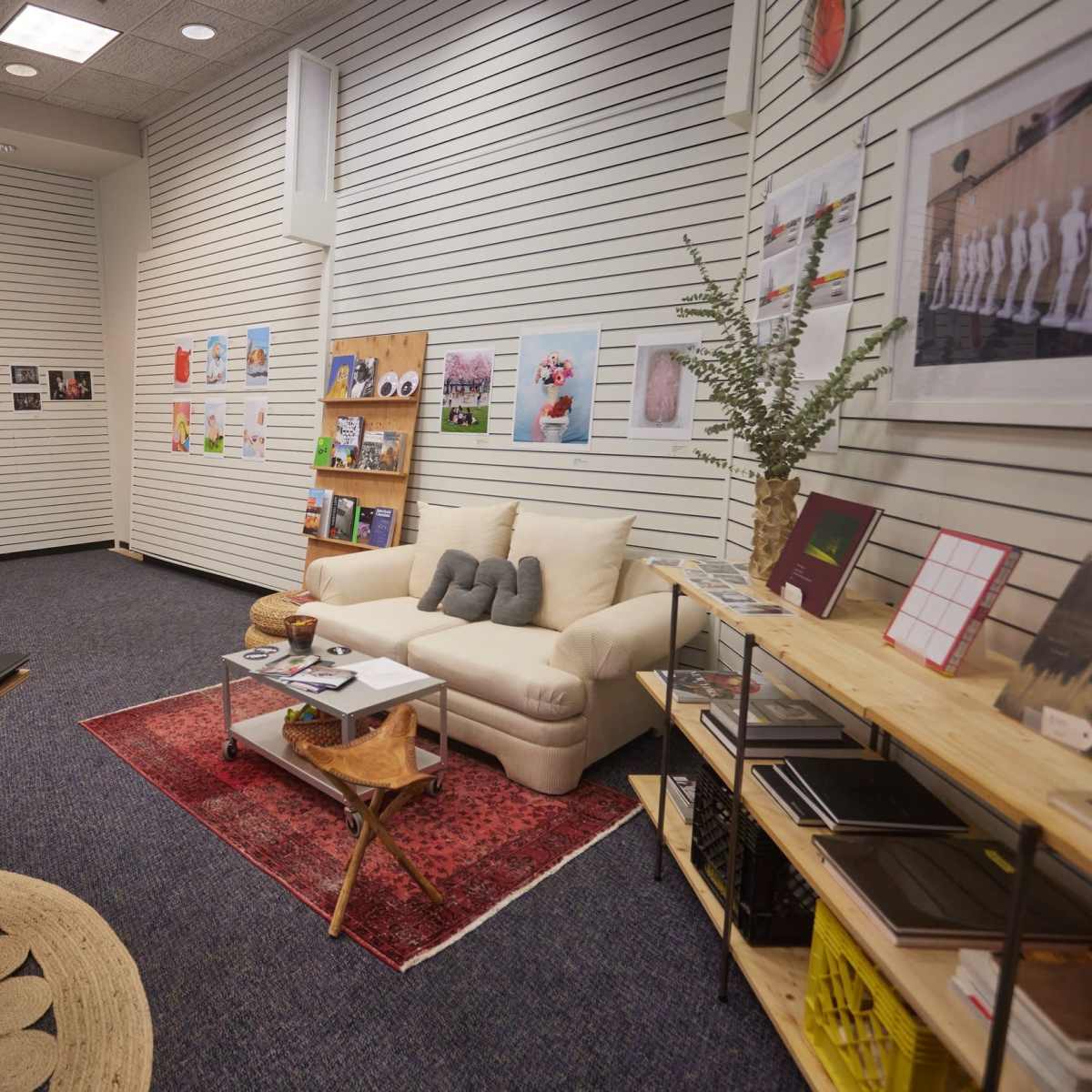 A cozy room with a sofa, a coffee table, display shelves, and walls adorned with artwork and photographs.