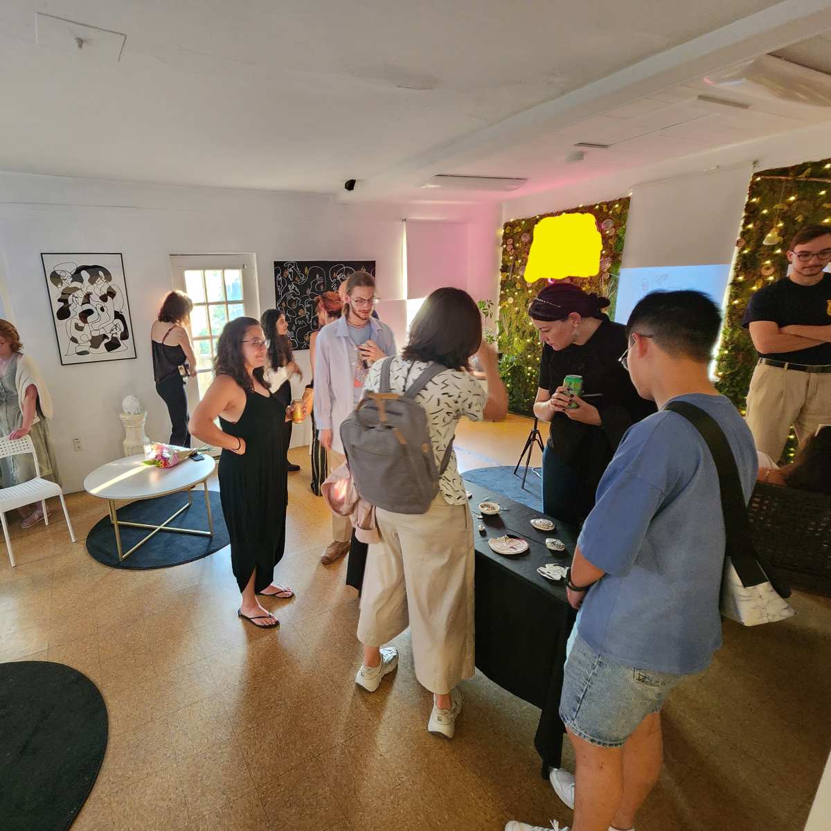 A group of people socialize in a brightly lit room furnished with a mix of modern furniture and decorations.