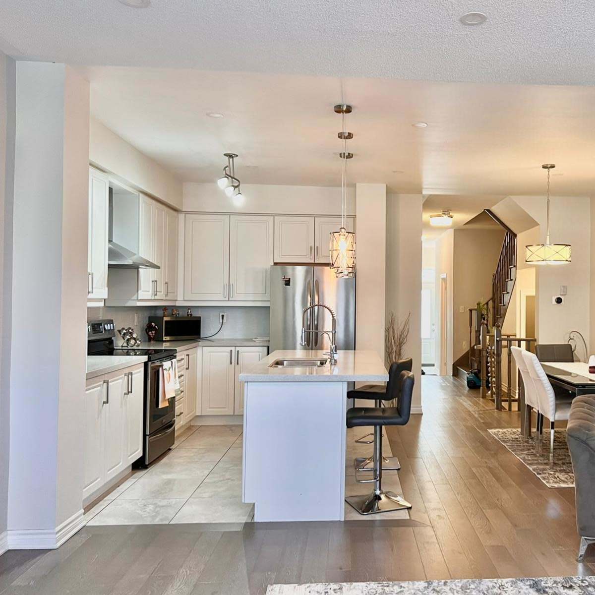 A modern open-concept kitchen and dining area with a staircase in the background.