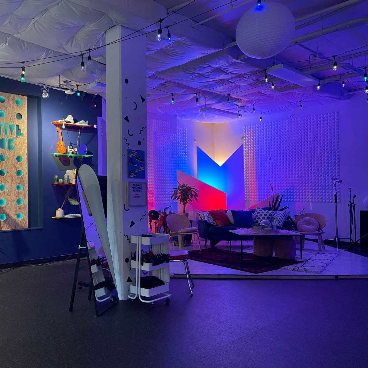 A vibrant creative space featuring a basketball hoop, colorful decor, and a lounge area with couches and art hanging on the walls.