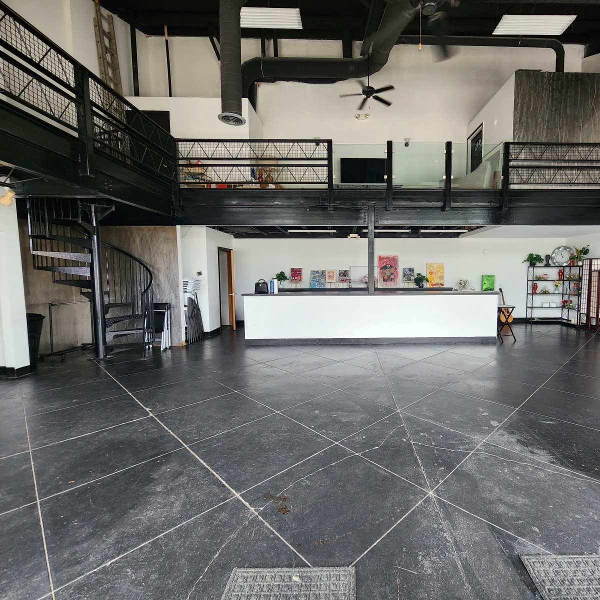The interior of a spacious commercial building features a two-level layout with a spiral staircase and a reception area at the front.