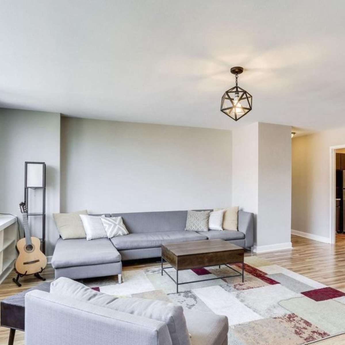 A modern living room with a sectional sofa, a coffee table, and large windows allowing natural light.