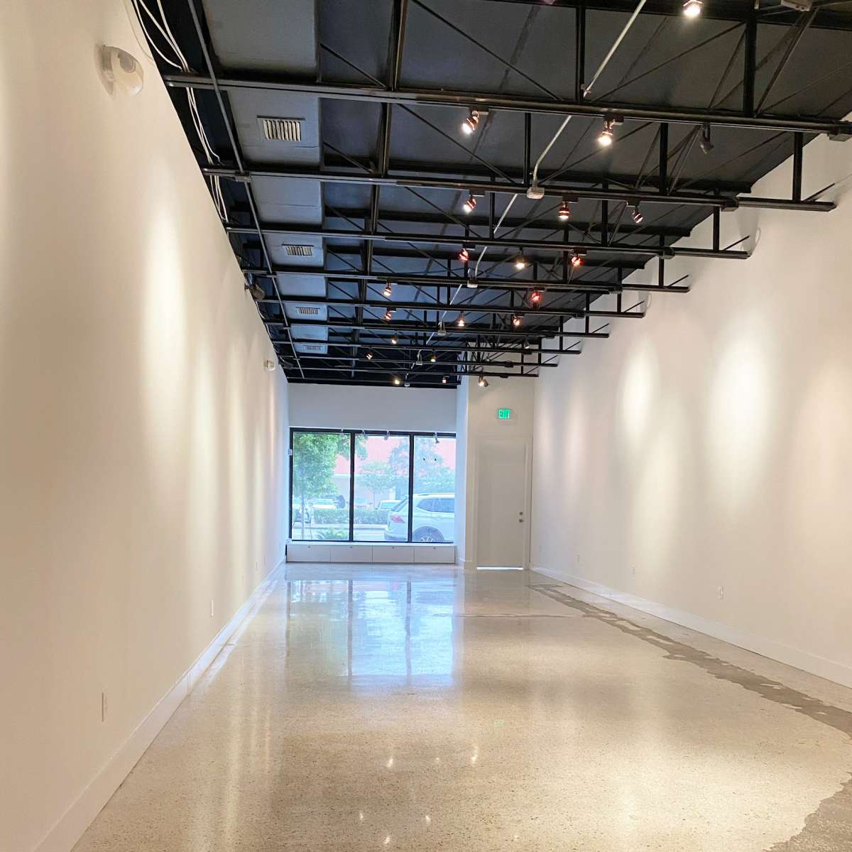 A spacious, empty room with polished concrete flooring and large windows at one end.