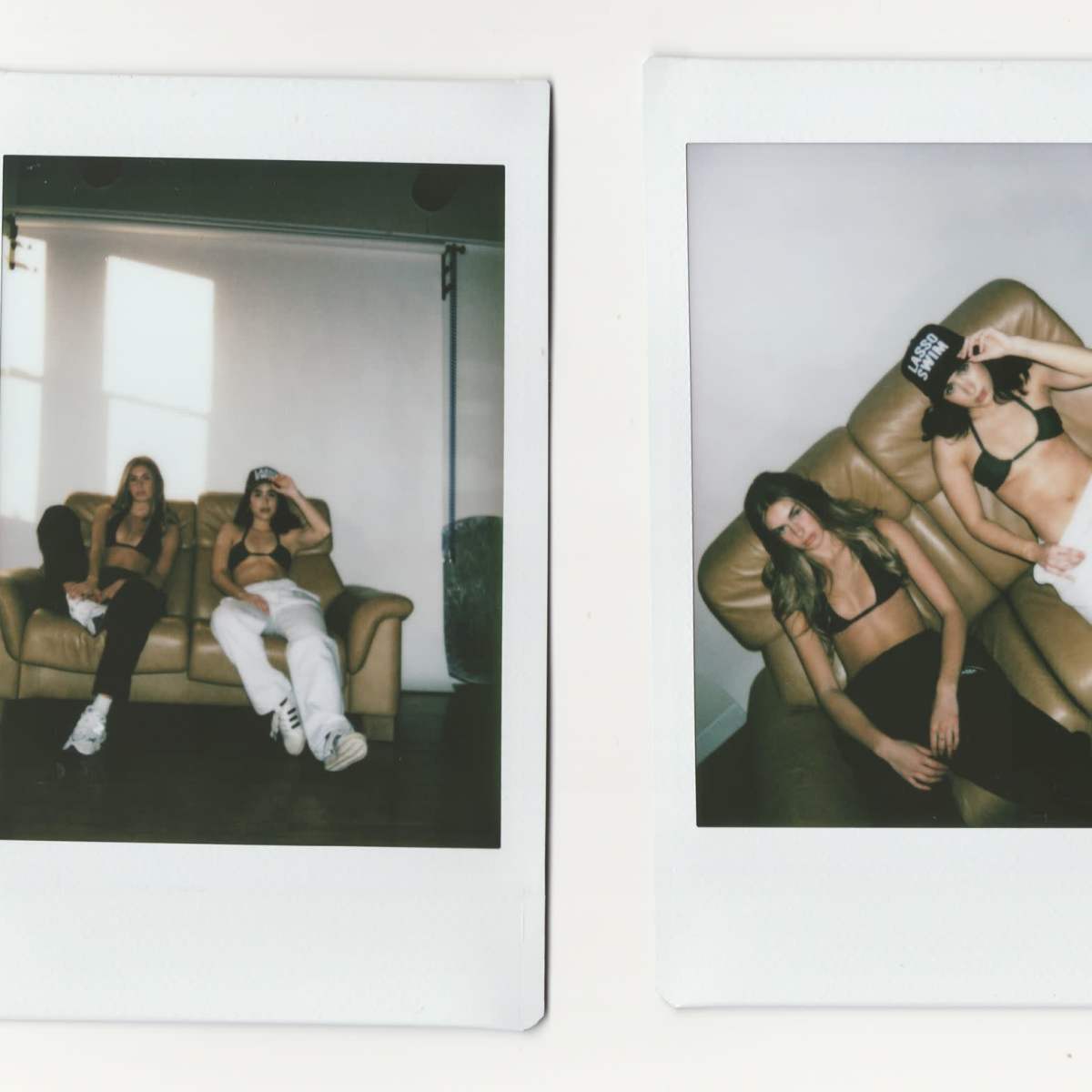 Two women are lounging on a brown sofa in a well-lit room, wearing casual clothing and hats.