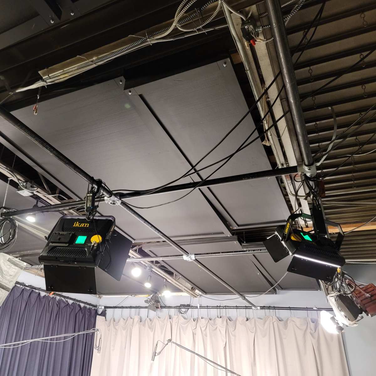 A studio ceiling with several lighting fixtures and hanging cables.
