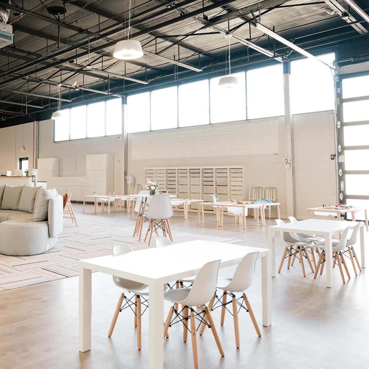A spacious, well-lit interior of a modern workspace with various seating arrangements and tables.