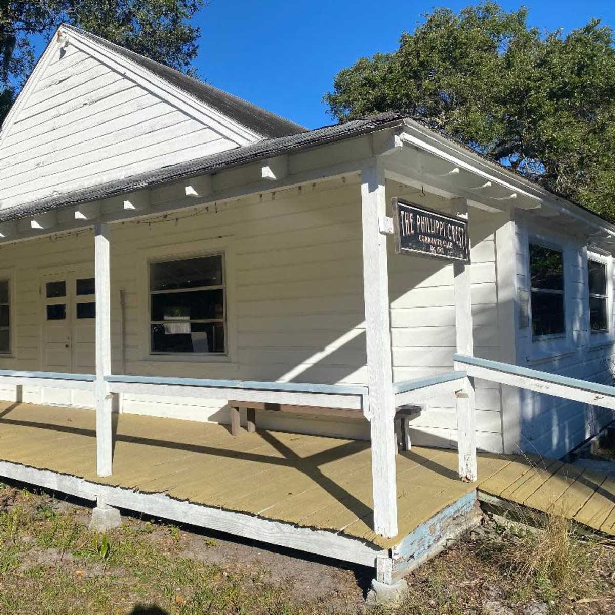 A white, wooden house with a front porch and a sign that reads "The Phillips House."