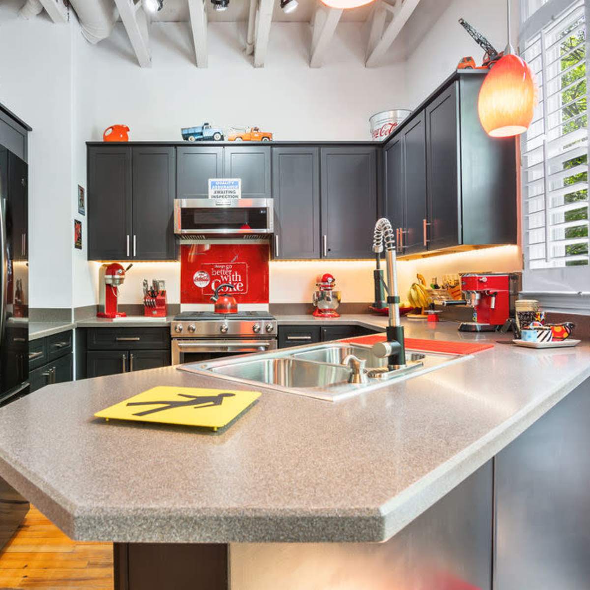 The kitchen features dark cabinetry, stainless steel appliances, and a central island with a yellow directional sign.