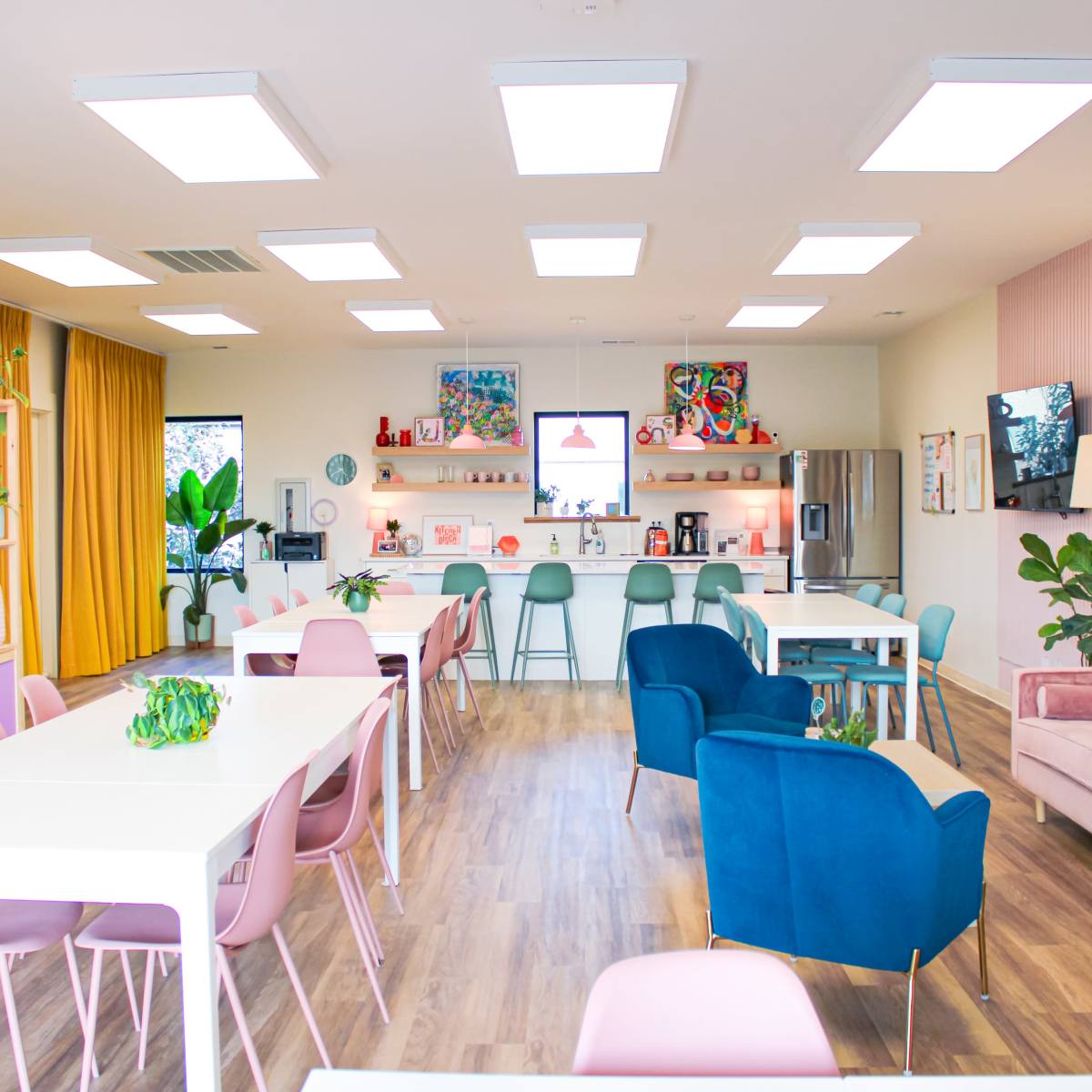 A brightly lit modern cafe features a mix of colorful seating arrangements and decorative shelving along the walls.