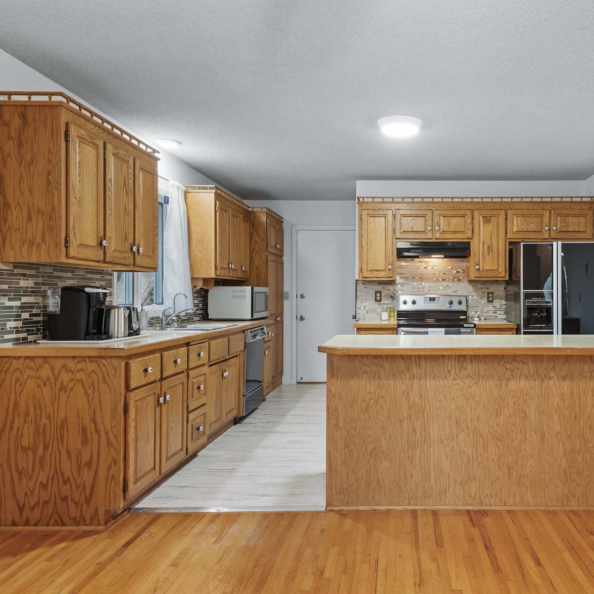 A kitchen with wooden cabinets, a countertop island, and stainless steel appliances.