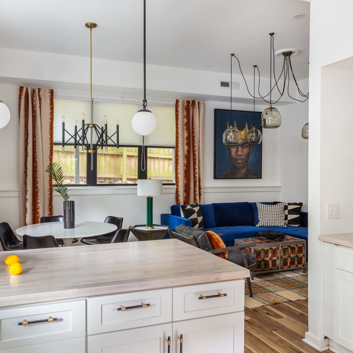 A modern living space featuring a blue sofa, a round dining table, and vibrant curtains, all set against a backdrop of contemporary decor.