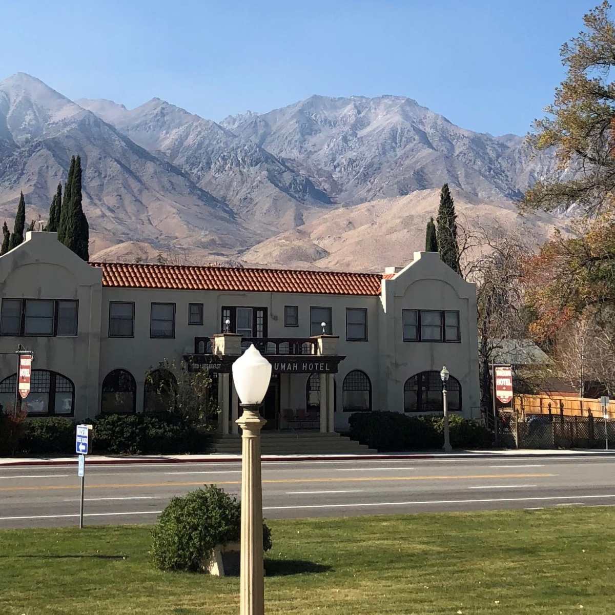 The front facade of the Manzanita Hotel, with mountains rising in the background under a clear sky.