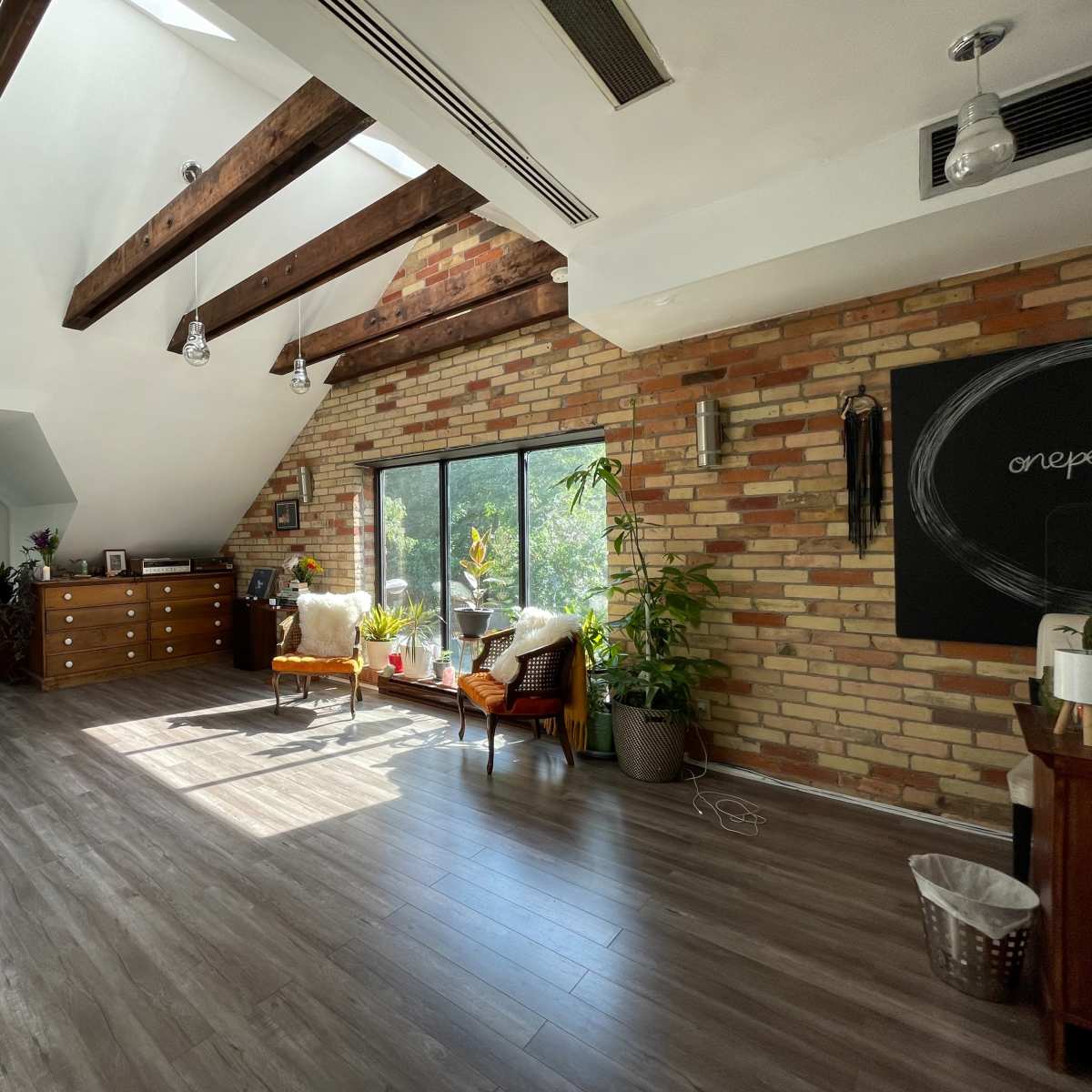 A spacious room with wooden beams, brick walls, large windows, and minimalist furniture.