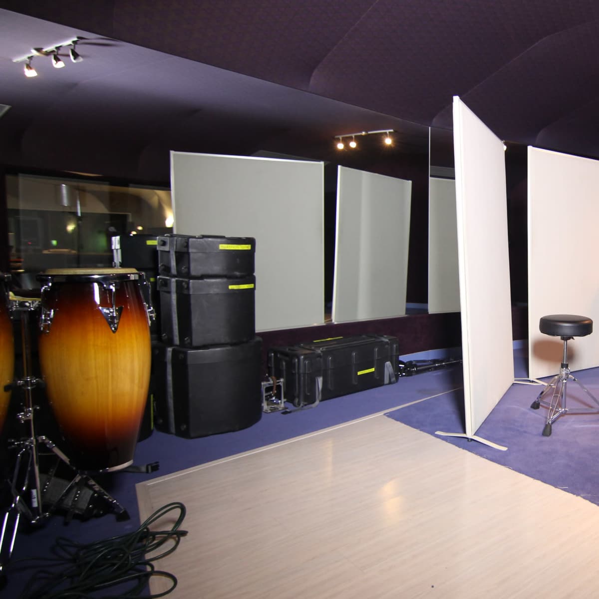 A soundproof recording studio with reflective panels, a microphone on a stand, a stool, and various music equipment.