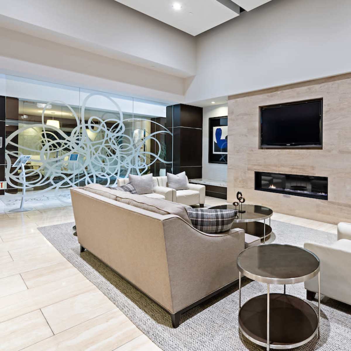 A modern lobby with a seating area featuring two sofas, a coffee table, and a wall-mounted television.