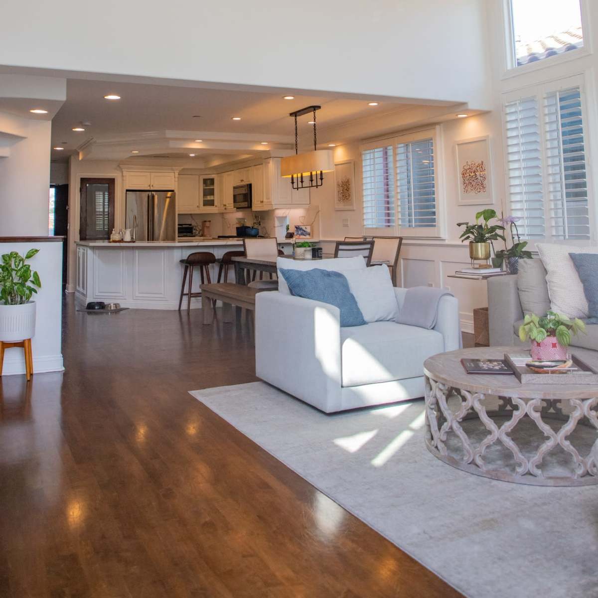 A well-lit open-concept living space with a seating area, dining area, and a kitchen in the background.