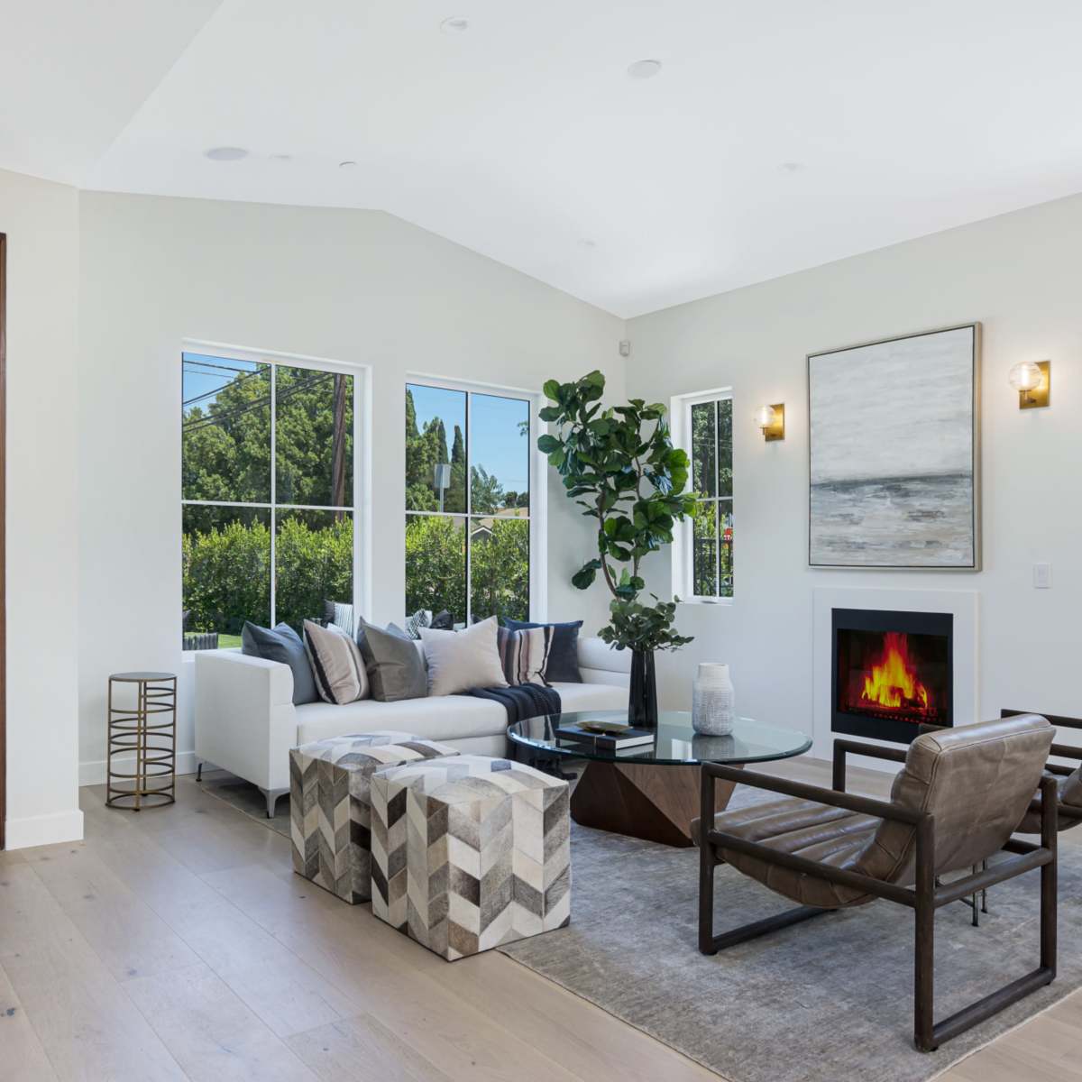 A bright living room with large windows, a modern fireplace, a comfortable sofa, and stylish seating arrangements.