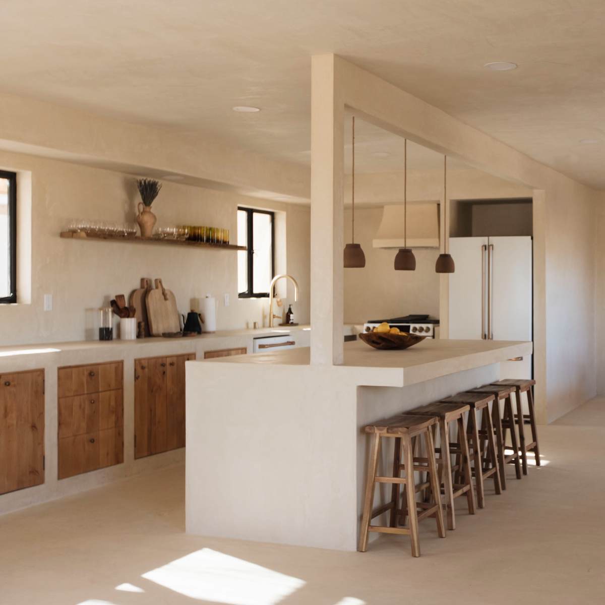 A spacious, minimalist kitchen features wooden cabinetry, a large island with bar stools, and a dining area with a wooden table in an open layout.