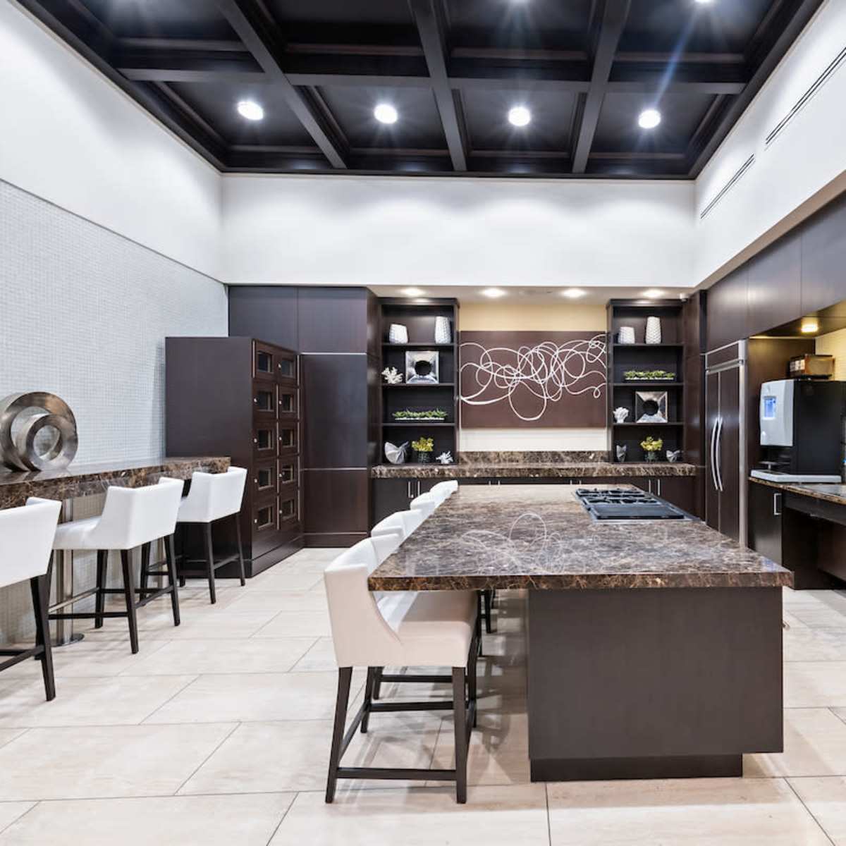 A modern kitchen featuring dark cabinetry, a large island with a marble countertop, and stainless steel appliances.