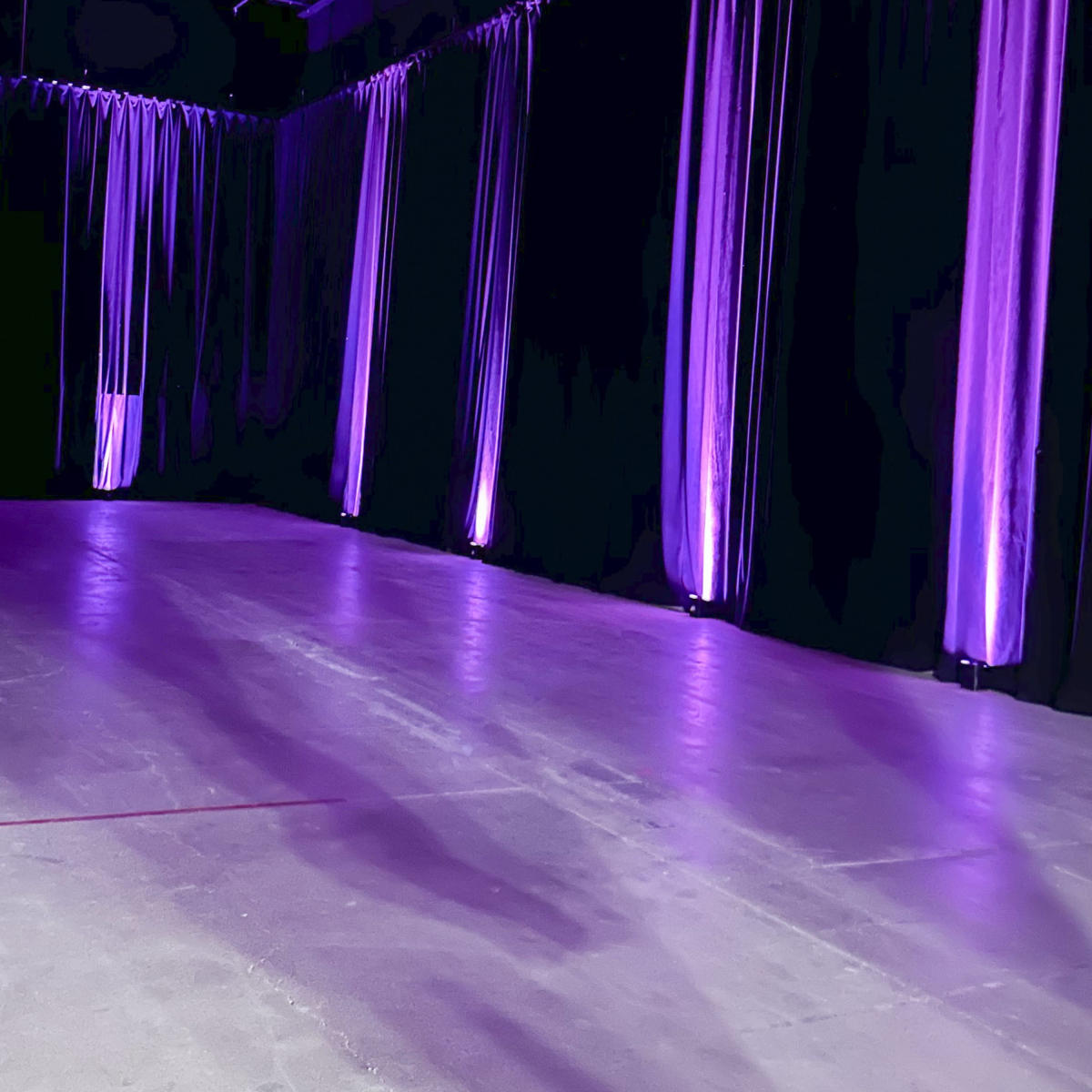 A dimly lit room with purple lighting and long fabric drapes along the walls.