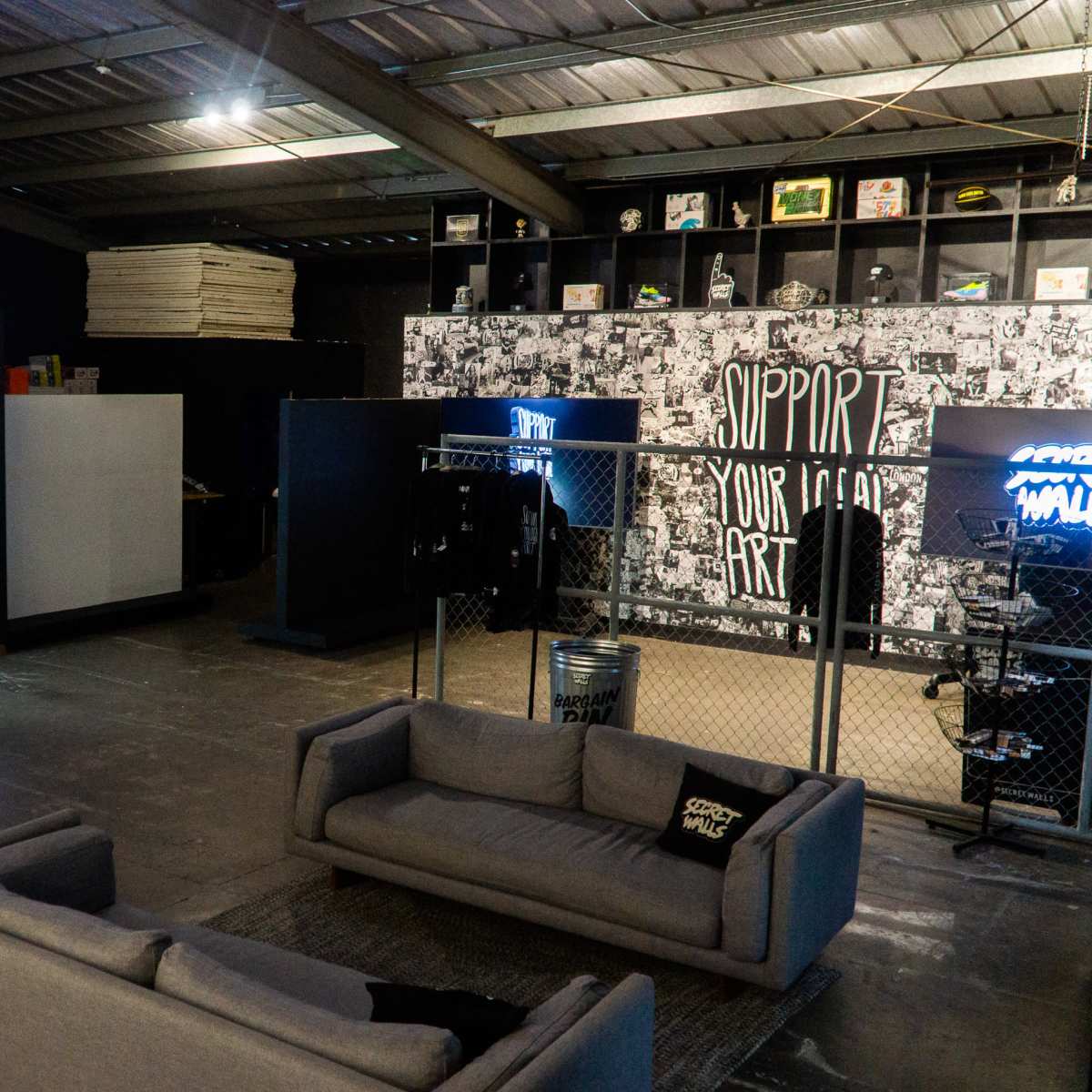 An industrial space with a seating area, a container-like room, and artistic wall displays.