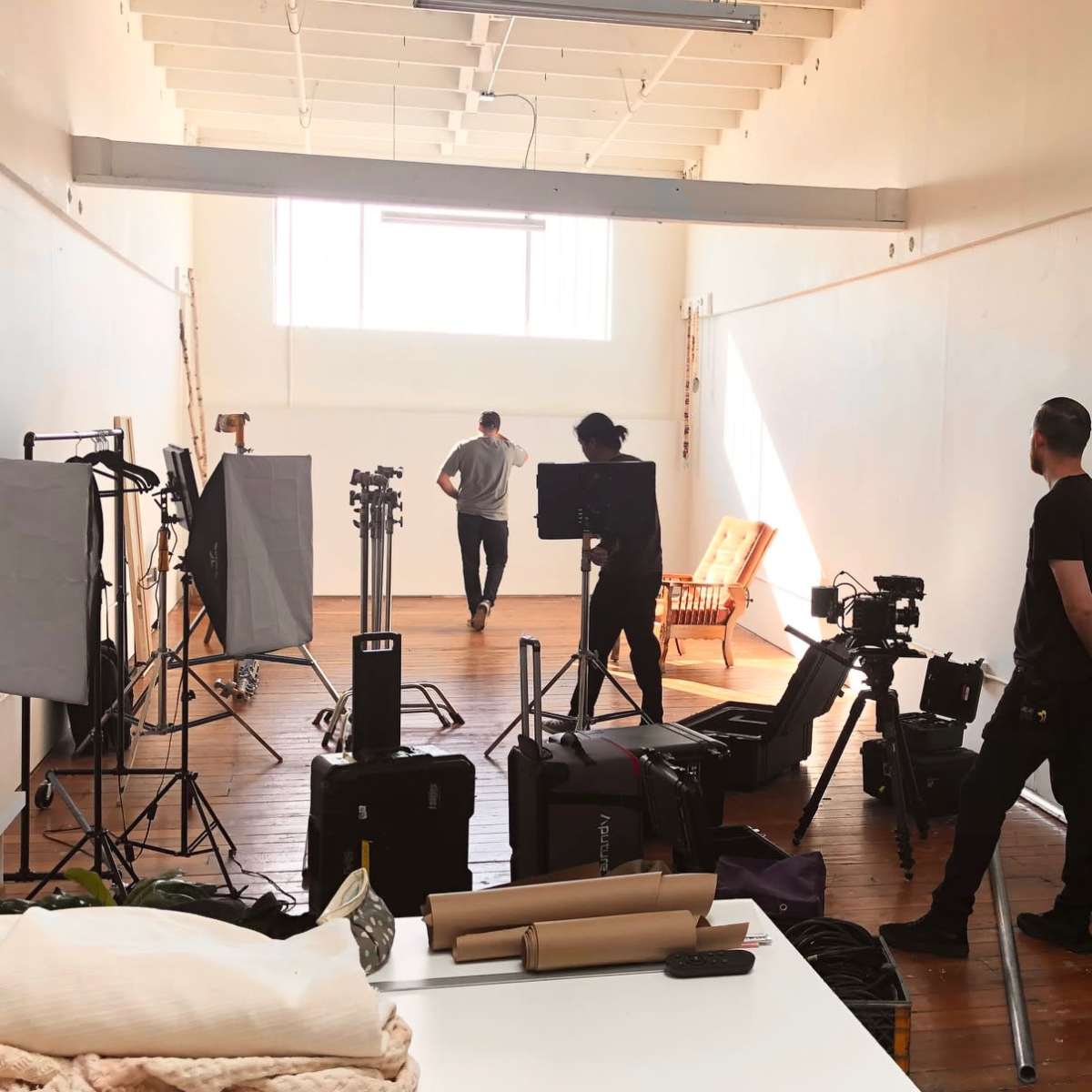 A photography studio is set up with various equipment and two people engaged in preparation activities.
