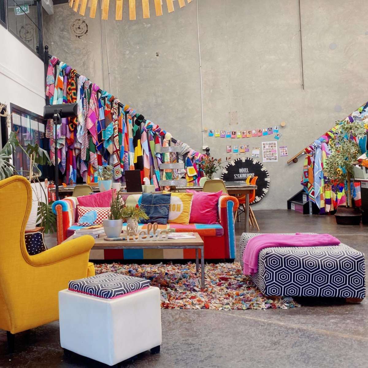 A vibrant communal space featuring colorful furniture, a bookshelf, and a wall decorated with fabric banners.