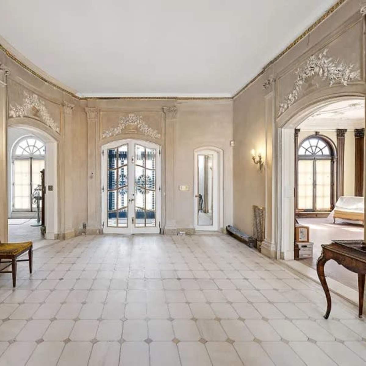 A spacious, elegantly designed hallway featuring arched doorways and decorative wall molding.