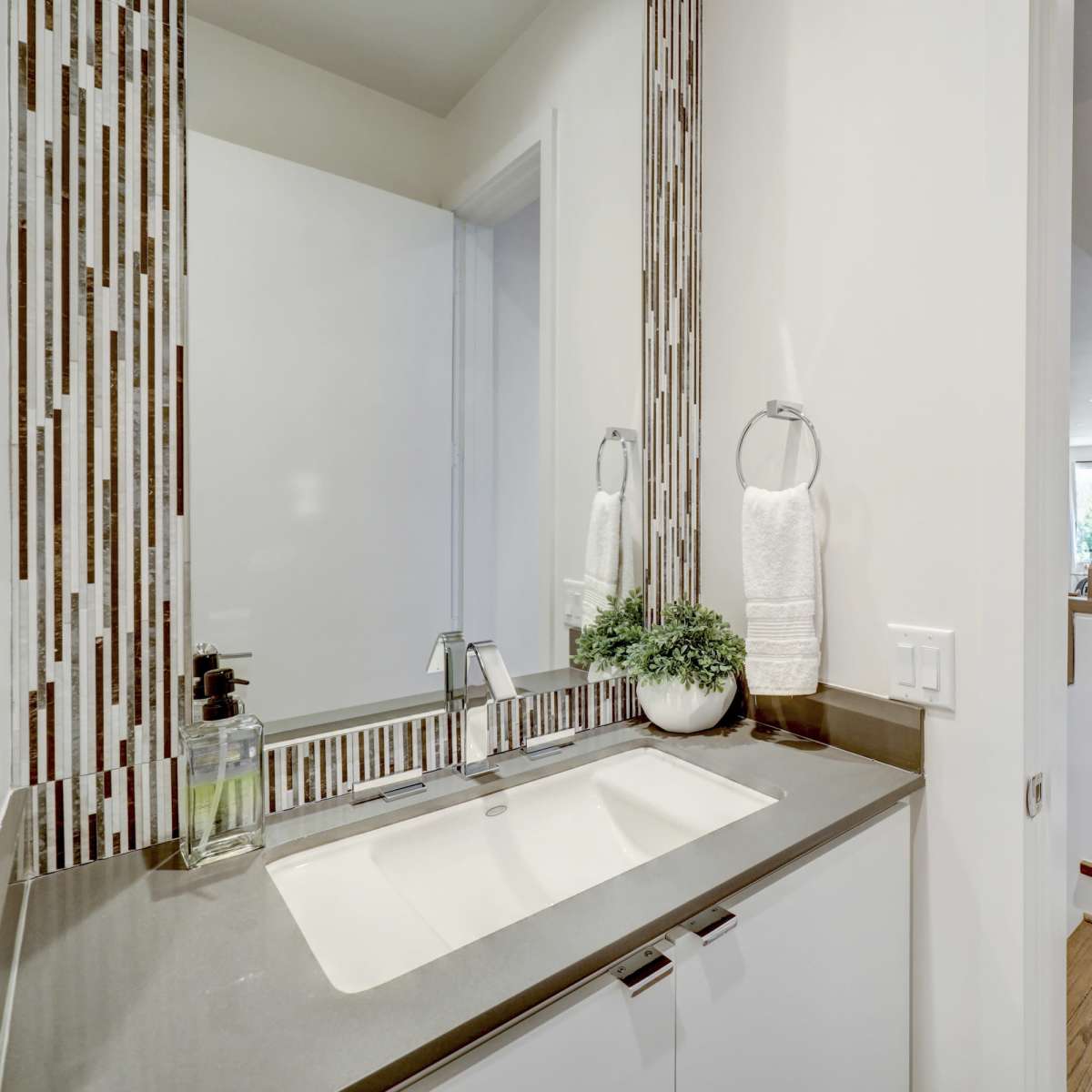A modern bathroom with a double sink vanity and a staircase leading upwards in the background.