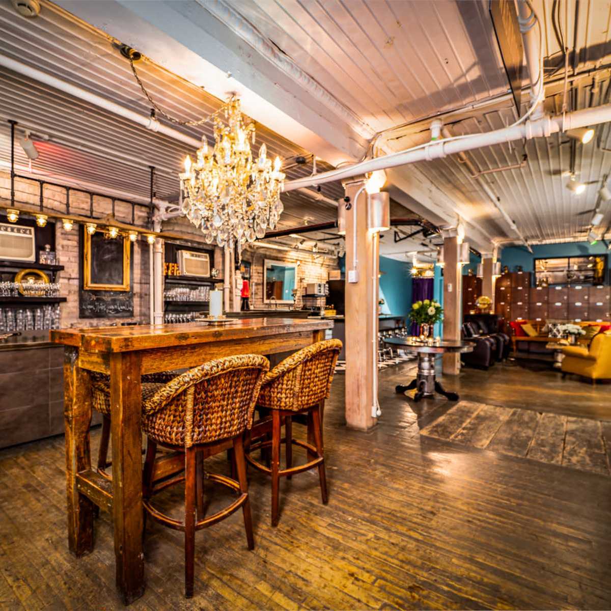 A spacious, well-lit bar area with wooden furniture, a chandelier, and various seating arrangements.