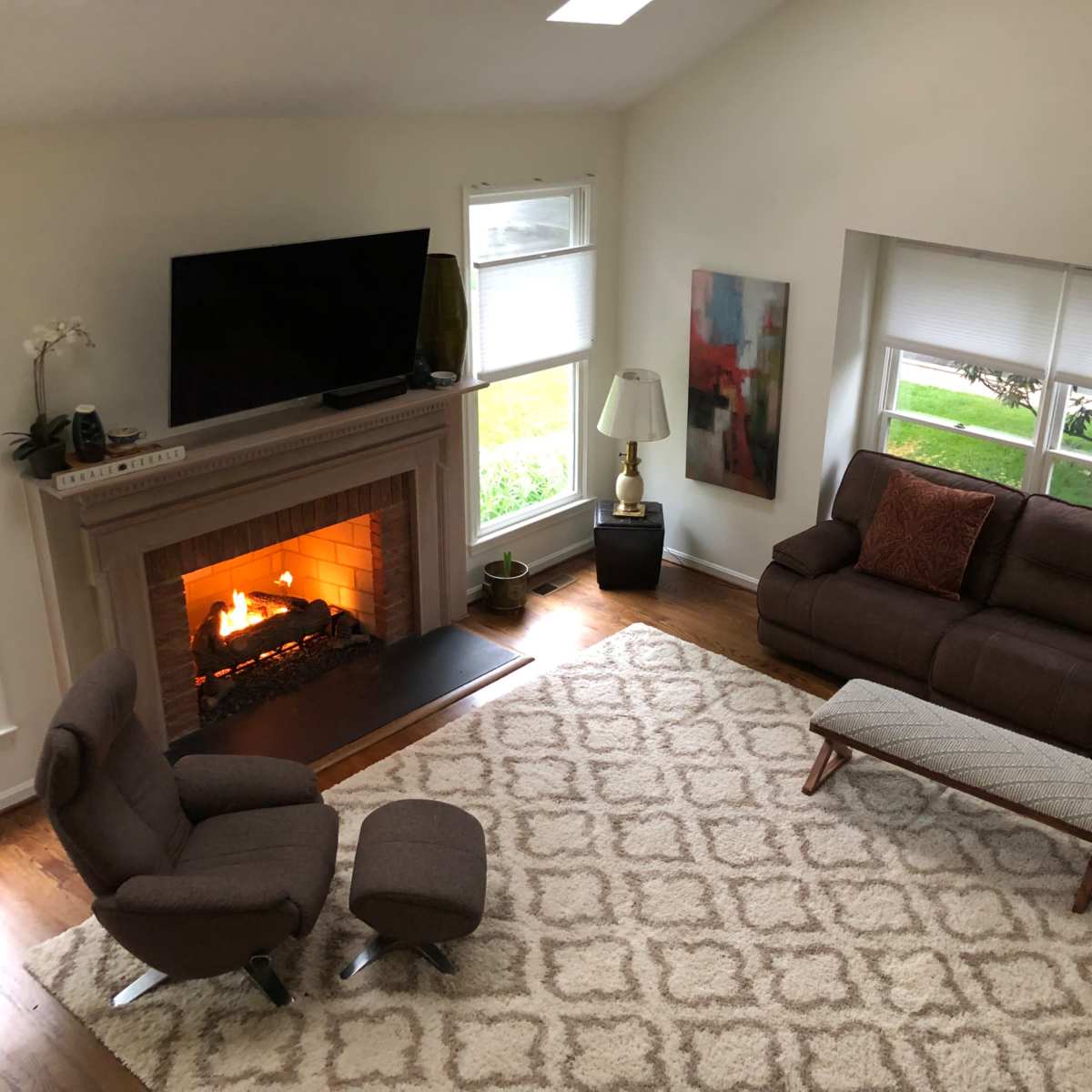 A living room with a fireplace, two sofas, a coffee table, and a television mounted on the wall.