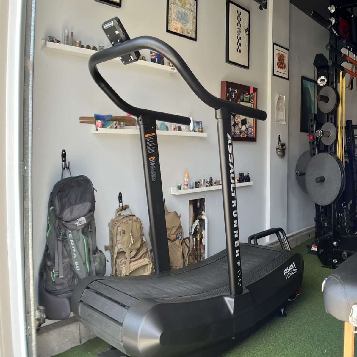 A home gym with a curved treadmill, exercise equipment mounted on walls, and a bench in a spacious room.